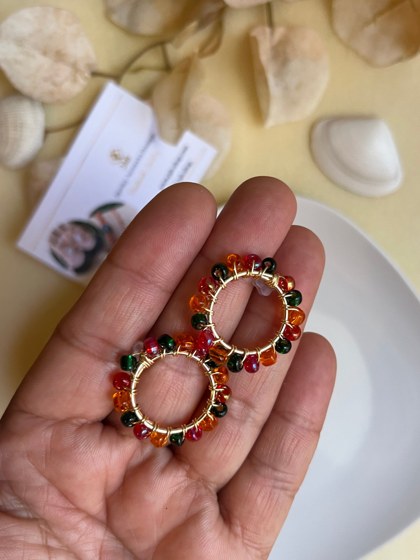 Hypoallergenic circular earrings with multicolored beads.