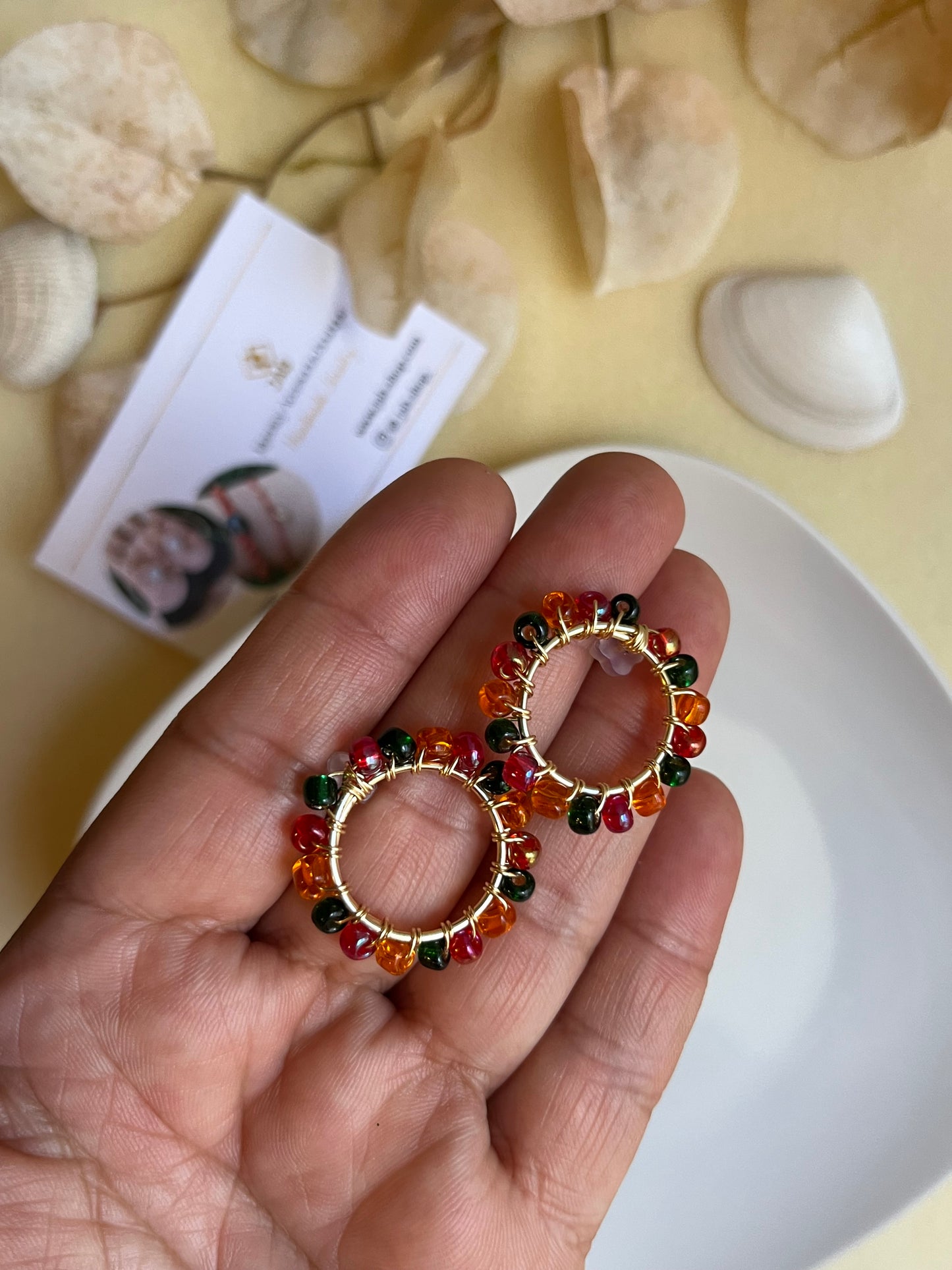 Hypoallergenic circular earrings with multicolored beads.