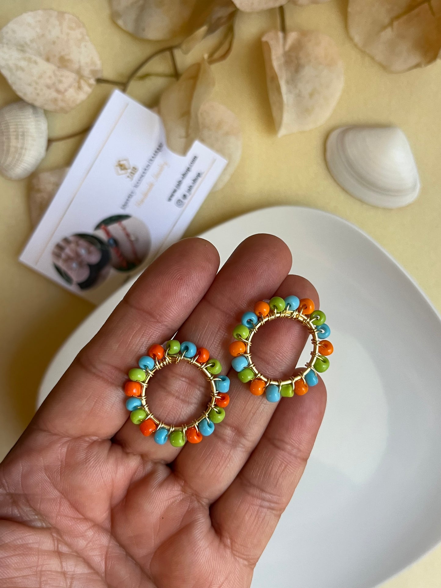 Hypoallergenic circular earrings with multicolored beads.