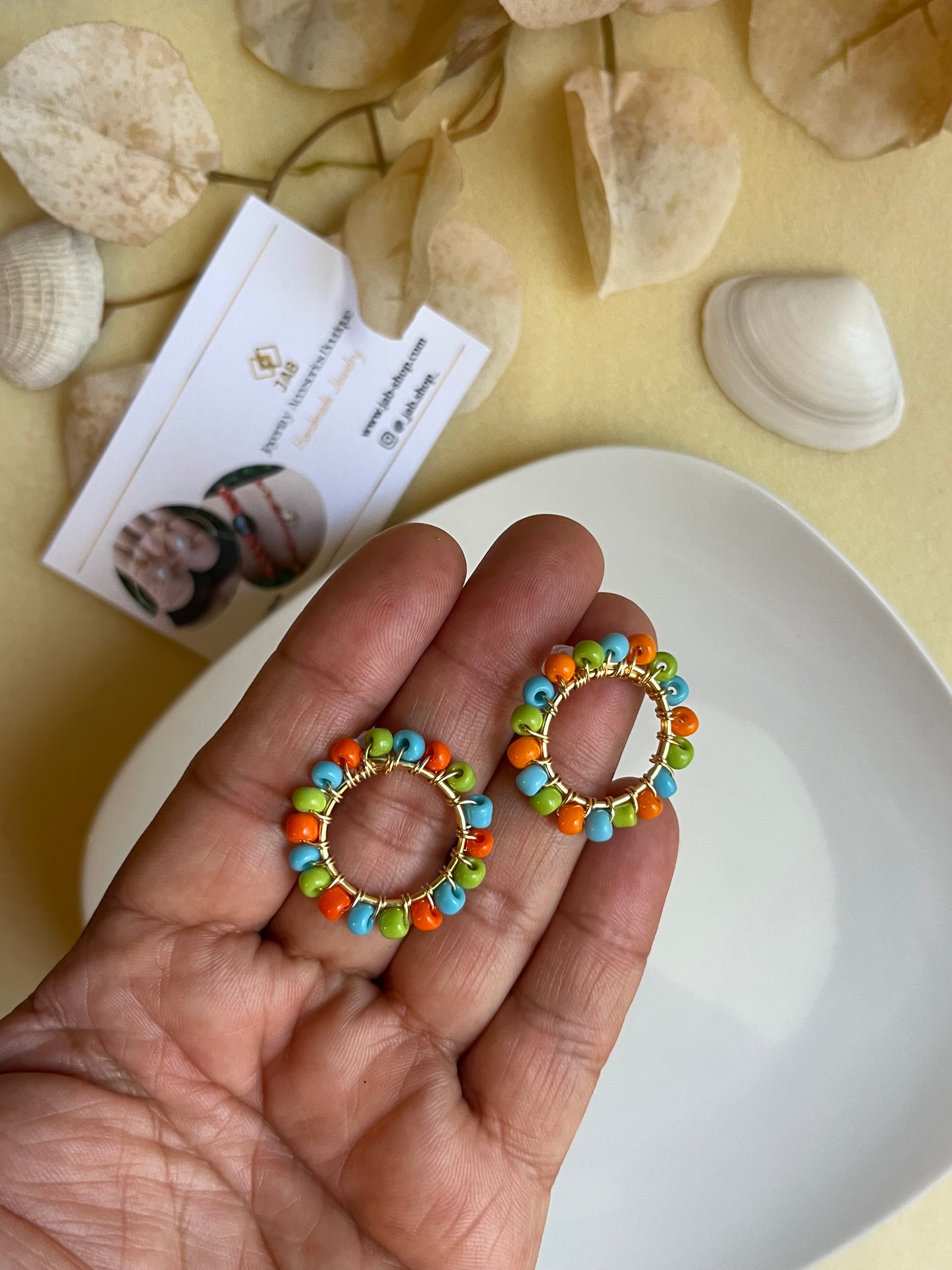 Hypoallergenic circular earrings with multicolored beads.