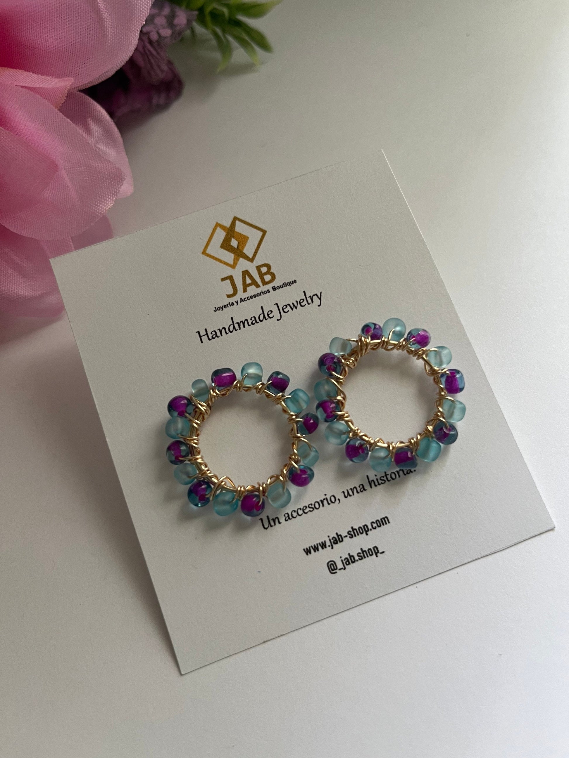 Hypoallergenic circular earrings with multicolored beads.